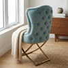 Cassander Dining Chair featuring a modern tufted design and golden frame, elegantly styled with a cozy throw.