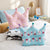 Crown Shaped Decorative Pillow in playful pink and blue designs on a cozy bed.