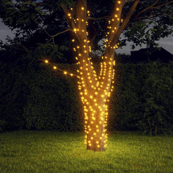 Solar-Powered LED String Lights 10M illuminating a tree at night in a garden setting.