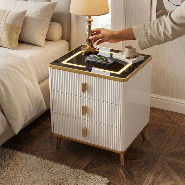 Smart Wireless Charging Bedside Table with Speakers next to a bed, featuring a lamp and charging devices on top.