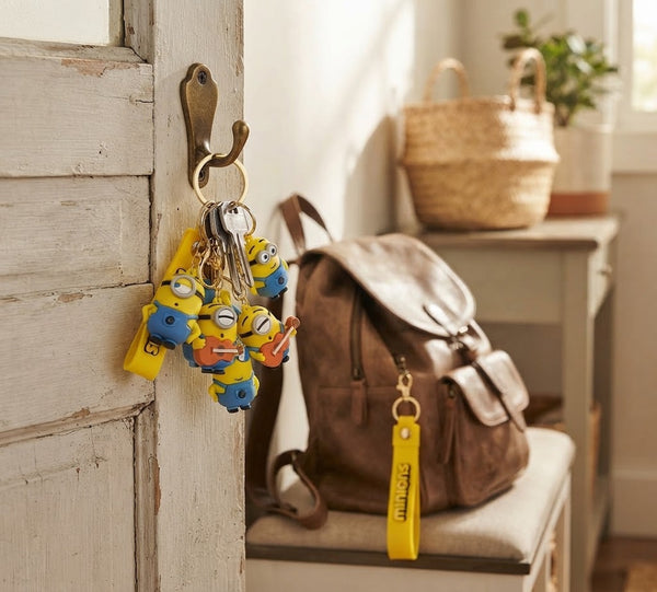 Colorful 3D Rubber Cartoon Character Keychain featuring Minions hanging from a hook near a brown bag.