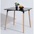 Compact Square Dining Table showcasing modern design with black top and wooden legs, perfect for small spaces.