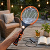 Rechargeable Electric Mosquito Killer Racket Fly Swatter eliminating flying insects in a garden setting.