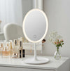 Oval LED Makeup Mirror with integrated lighting on a vanity table, enhancing beauty routines with clear reflection.