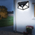 114 Solar Motion Sensor LED Wall Light mounted on a wall, illuminating outdoor space in the evening.