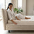 Modern Hotel Upholstered Platform Bed Frame with a woman in cozy pajamas sitting on the edge of the bed.