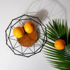 Geometric Iron Fruit Storage Basket with oranges and wooden base on a clean background.