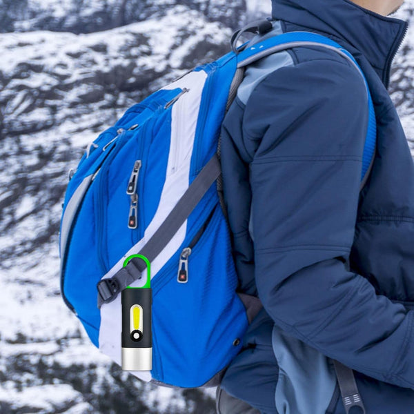 Portable Waterproof COB LED Rechargeable Keychain Light attached to a blue backpack on a person in a snowy landscape.