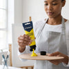 Acrylic Paint 75ml - Lemon Yellow being squeezed onto a wooden palette by a woman in an art studio.