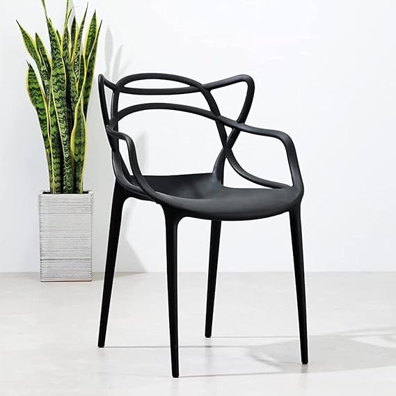 Cafe Replica Master Chair in black against white wall with a plant in a pot.
