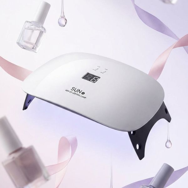 Beauty Nail Supplies LED UV Light 48W Nail Lamp shown with nail polish bottles in a stylish setting.
