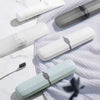 Compact Travel Toothbrush & Utensil Storage Case in various colors on a soft surface with a toothbrush.