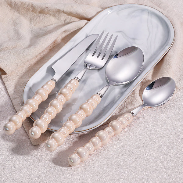 Elegant Pearl-Handled Stainless Steel Cutlery Set displayed on a marble plate, featuring a knife, fork, and spoons.