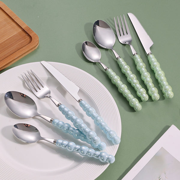 Elegant Pearl-Handled Stainless Steel Cutlery Set featuring blue and green pearl handles on a white plate.