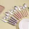 Elegant Pearl-Handled Stainless Steel Cutlery Set displayed on a table with a plate and wooden tray.