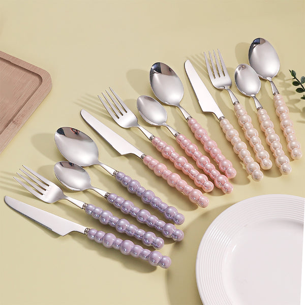 Elegant Pearl-Handled Stainless Steel Cutlery Set displayed on a table with a plate and wooden tray.