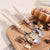 Elegant Pearl-Handled Stainless Steel Cutlery Set with spoons and snacks on a wooden tray