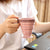 A person holding a foldable silicone travel cup at a desk, showcasing its compact and collapsible design.
