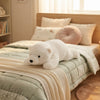 Polar Bear Plush Toy resting on a bed with light green bedding, perfect for children's playtime and bedroom décor.