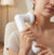 A woman using a Handheld Body Massager on her neck for relaxation and relief.