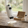 Mini Portable Microscope on a wooden table with specimen slides and tools in the background.