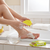 Person using Beauty Banana Milk Mini Whitening Soap for foot care in a bathroom setting.