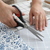 11-inch Stainless Steel Clothing Scissors cutting fabric on a sewing table.