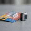 Compact Mini Digital Camera beside its packaging on a gray surface.