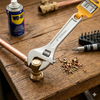 Professional Adjustable Torque Wrench in action with copper pipes and tools on a wooden surface.