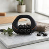Multi-Roller Muscle Massage Tool on a marble countertop with towels and plants in the background.