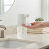 300ml Liquid Soap & Lotion Dispenser dispensing soap onto a hand near a sink, showcasing its clear design and functionality.
