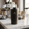 350ml Stainless Steel Travel Mug on a kitchen counter with coffee equipment in the background.