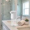 300ml Liquid Soap & Lotion Dispenser on bathroom countertop next to towels and a plant.