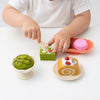 Child playing with Pretend Bakery Treats Play Set, featuring colorful desserts like macarons and cake pieces.