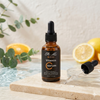 Vitamin C Brightening Face Serum in a dropper bottle with citrus and green leaves in the background.