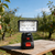 9W 1440LM Outdoor Camping Emergency Flashlight Work Light on a wooden table in an orchard.