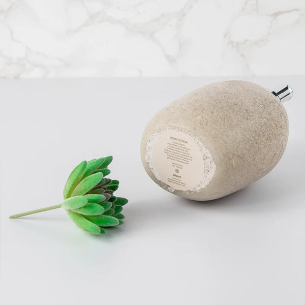 Home Decor Vase Luxury Hand Wash Soap Dispenser in natural stone finish with plant on marble background.