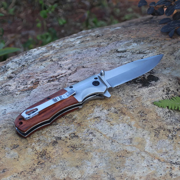 Wooden Handle Folding Tactical Pocket Knife displayed on a natural rock surface, showcasing its elegant design and sharp blade.
