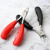 Professional Nail Cutter Nipper for Thick Nails with red and black handles on a marble surface.