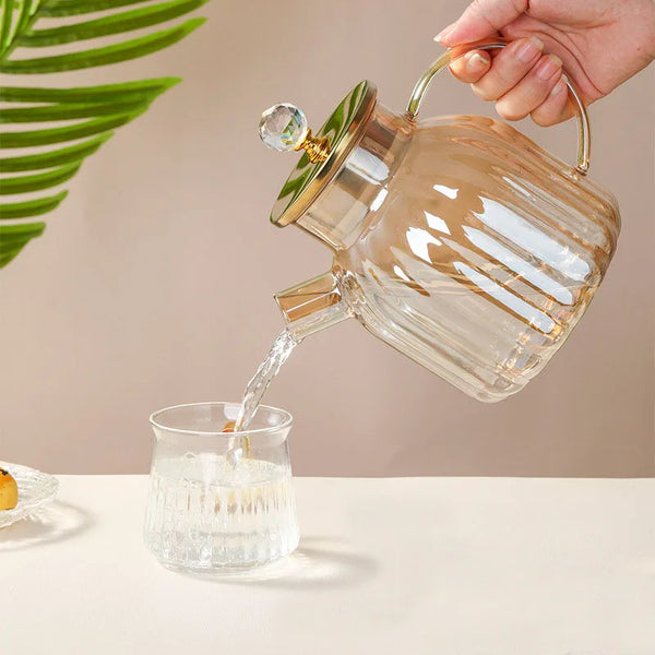 Elegant Large Capacity All-Glass Tea Set pouring tea into a glass cup with a golden handle and attractive design.