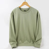 Unisex Oversized Blank Hoodies in soft green color hanging on a wooden hanger, showcasing its relaxed fit.