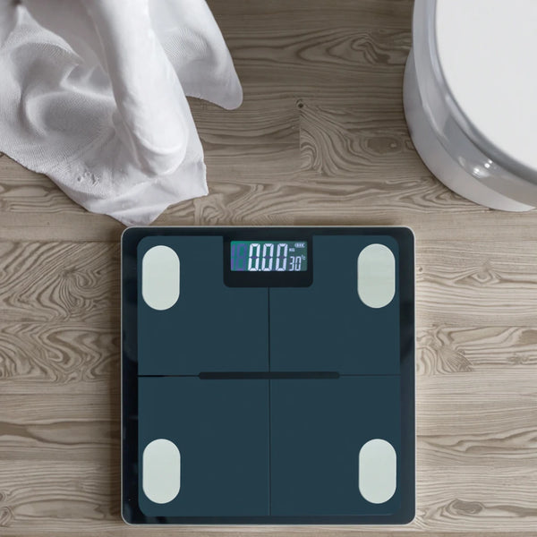 Bluetooth Digital Smart Bathroom Scale on wooden floor next to a towel and toilet.