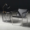 Modern MDF Veneer Dining Table: Sleek black modern chair with metallic frame beside a wire basket table and stylish lamp in a contemporary setting.