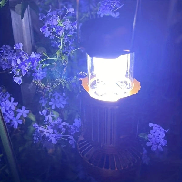 Solar LED Camping Lamp with Fan illuminating flowers at night, providing light and cooling for outdoor adventures.