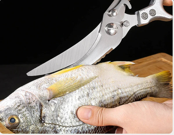 Chicken Shredder Tool: Hand holding a fish while cutting with a stainless steel kitchen scissor for fish preparation.