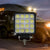 Waterproof Off-Road LED Work Light illuminating outdoor area at night with vehicle in background.
