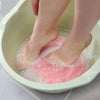 Person using Soft Body Massage Bath Brush to exfoliate feet in a water bath.