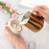 Gold Stainless Steel Milk Frothing Pitcher 350ML pouring milk into a cup for latte art.
