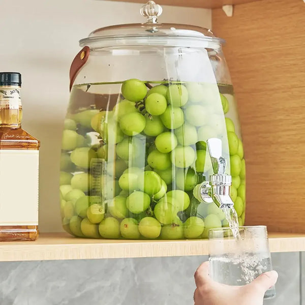 Large Glass Beverage Dispenser with Faucet filled with green grapes, stylishly serving drinks.