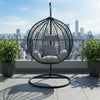 Stylish Modern Indoor-Outdoor Swing Chair on a balcony with city skyline view and green plants.